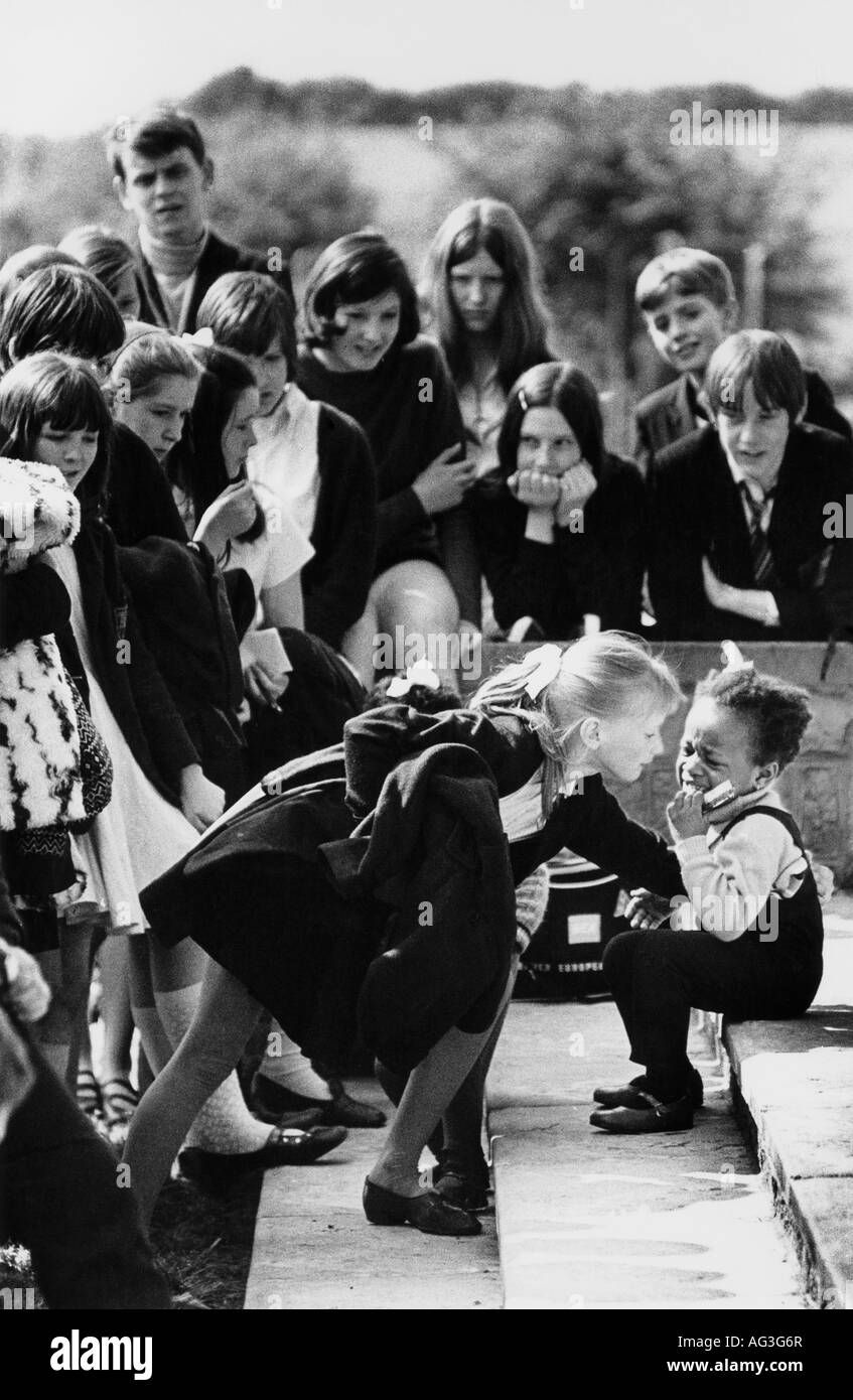 L'annata 1969 bw Maltby stampa S. Yorks degli alunni della scuola secondaria si affollano attorno a un po' di nero ragazza che è caduto ed è il pianto Foto Stock