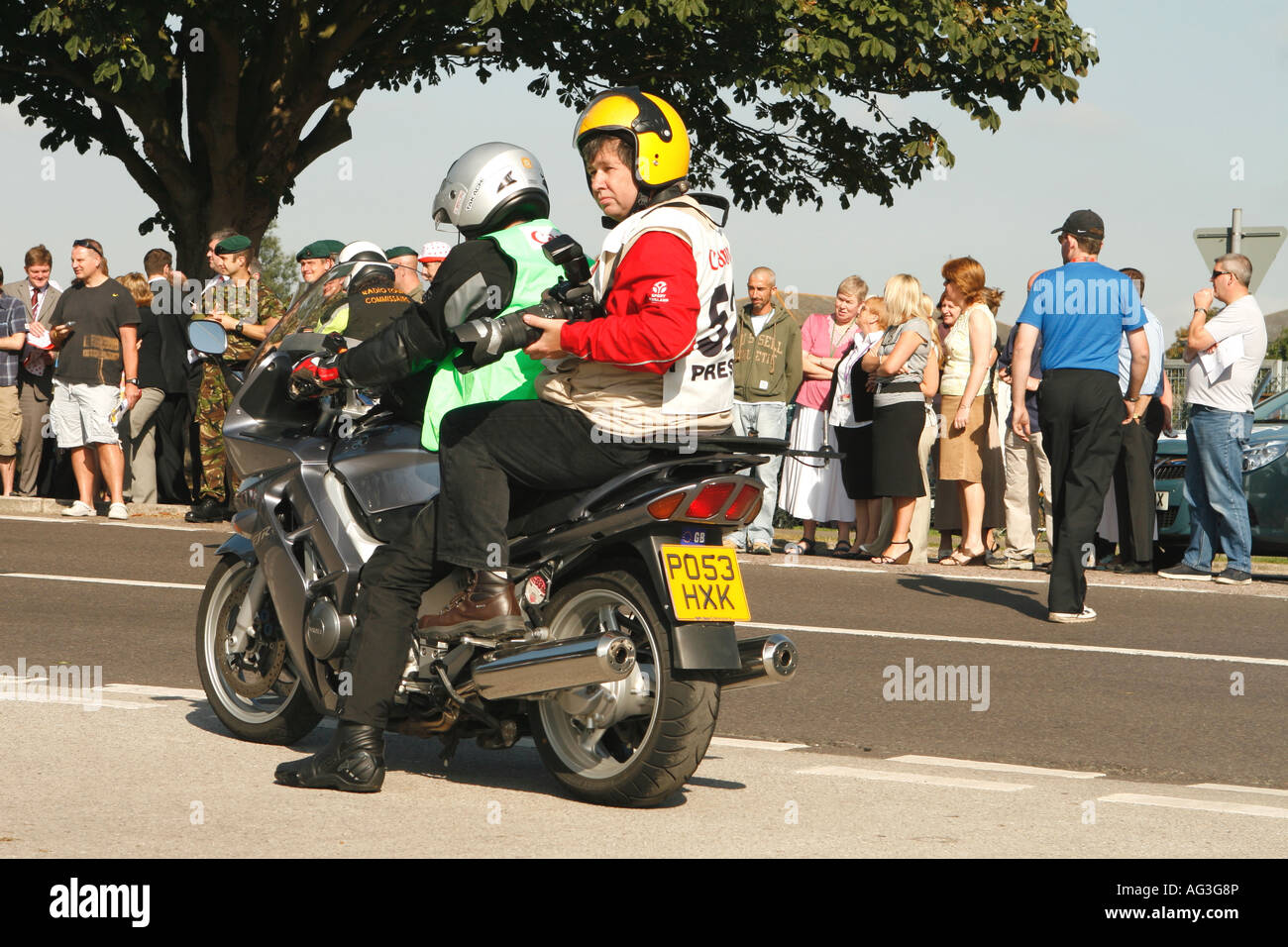Fotografo sportivo con telecamera e obiettivo a lungo seduto sul retro della moto che copre il tour della Gran Bretagna cycle race Foto Stock