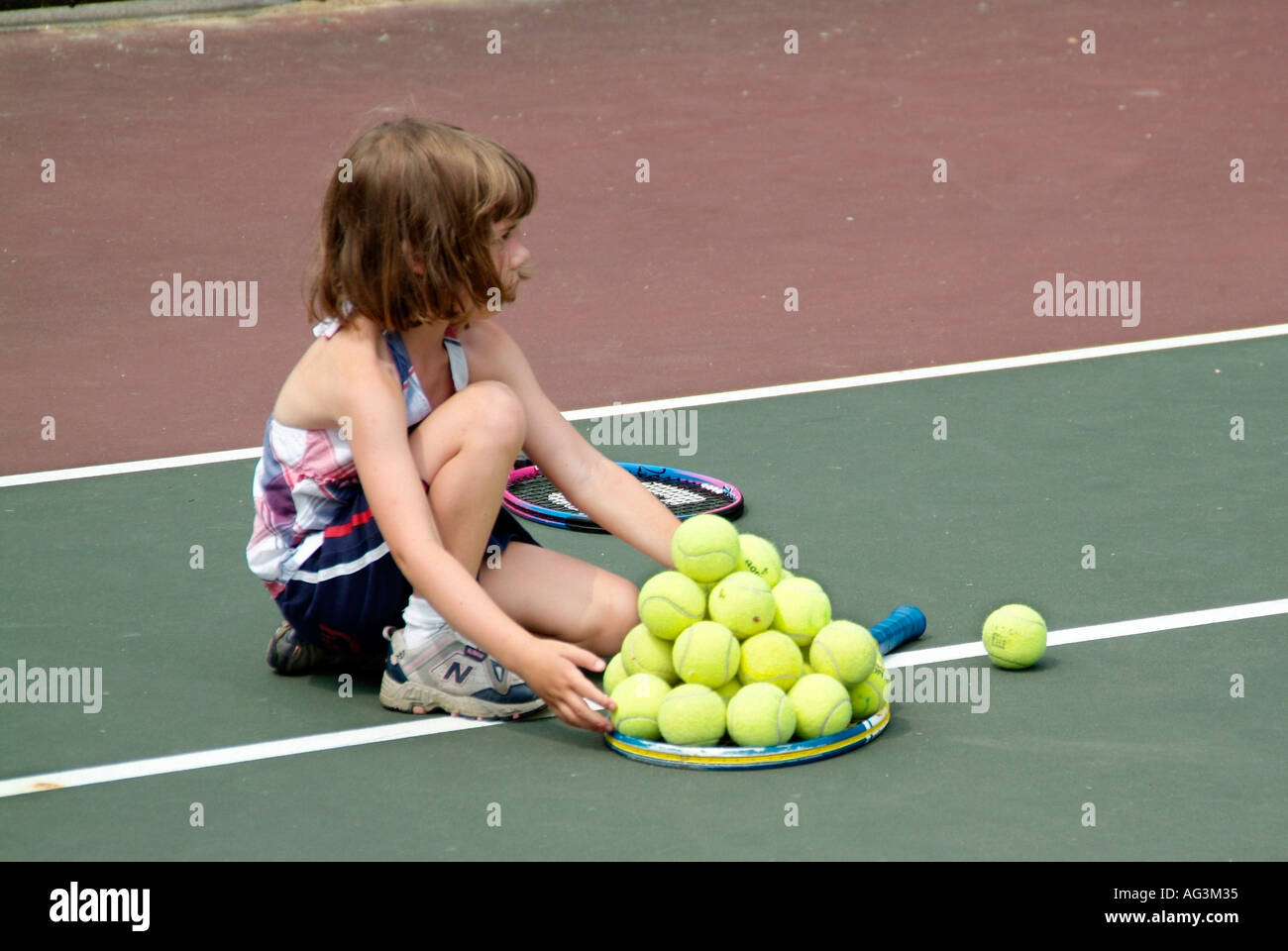 4 e 5 anni i bambini gruppo di prendere lezioni di tennis insegnata da studenti del college a un pubblico campo da tennis Foto Stock
