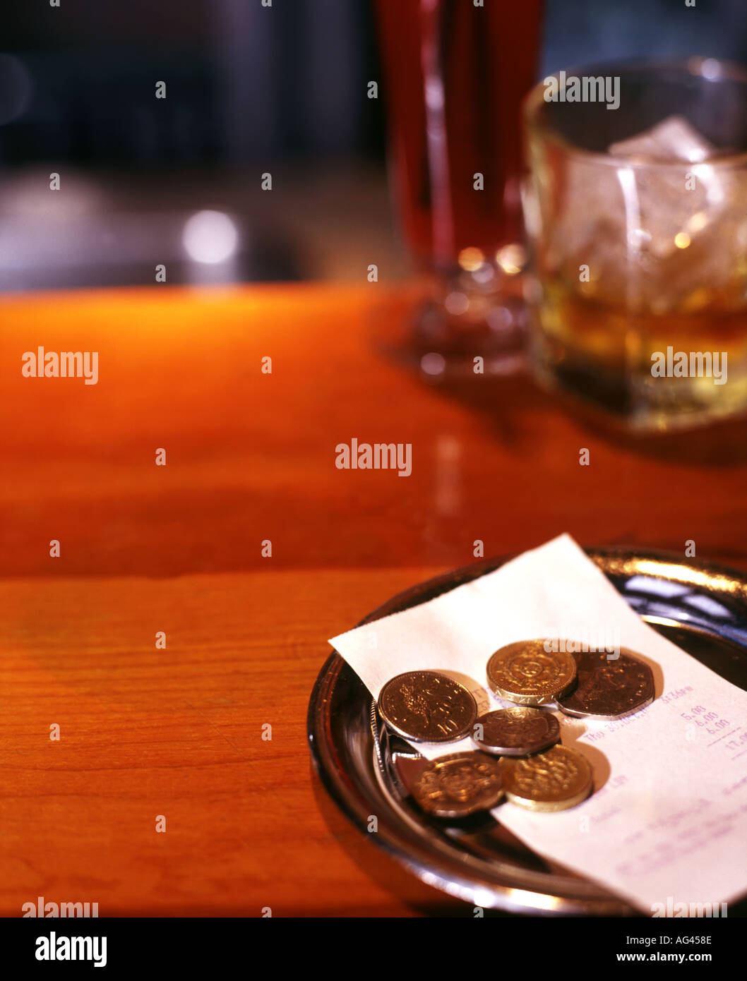 Le monete in un vassoio di punta con bevande in background Foto Stock