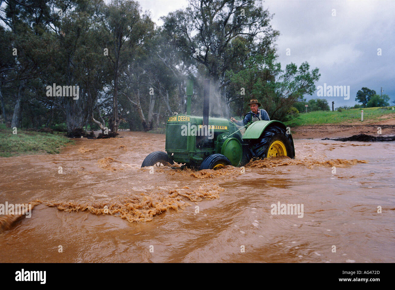 Trattore John Deere attraversando un invaso creek in Australia Foto Stock