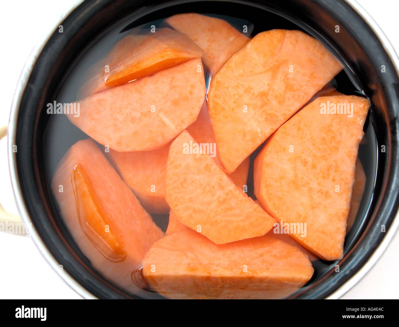 Patate dolci pelate e tagliate in pezzi in acqua per la cottura di tipo speciale Foto Stock