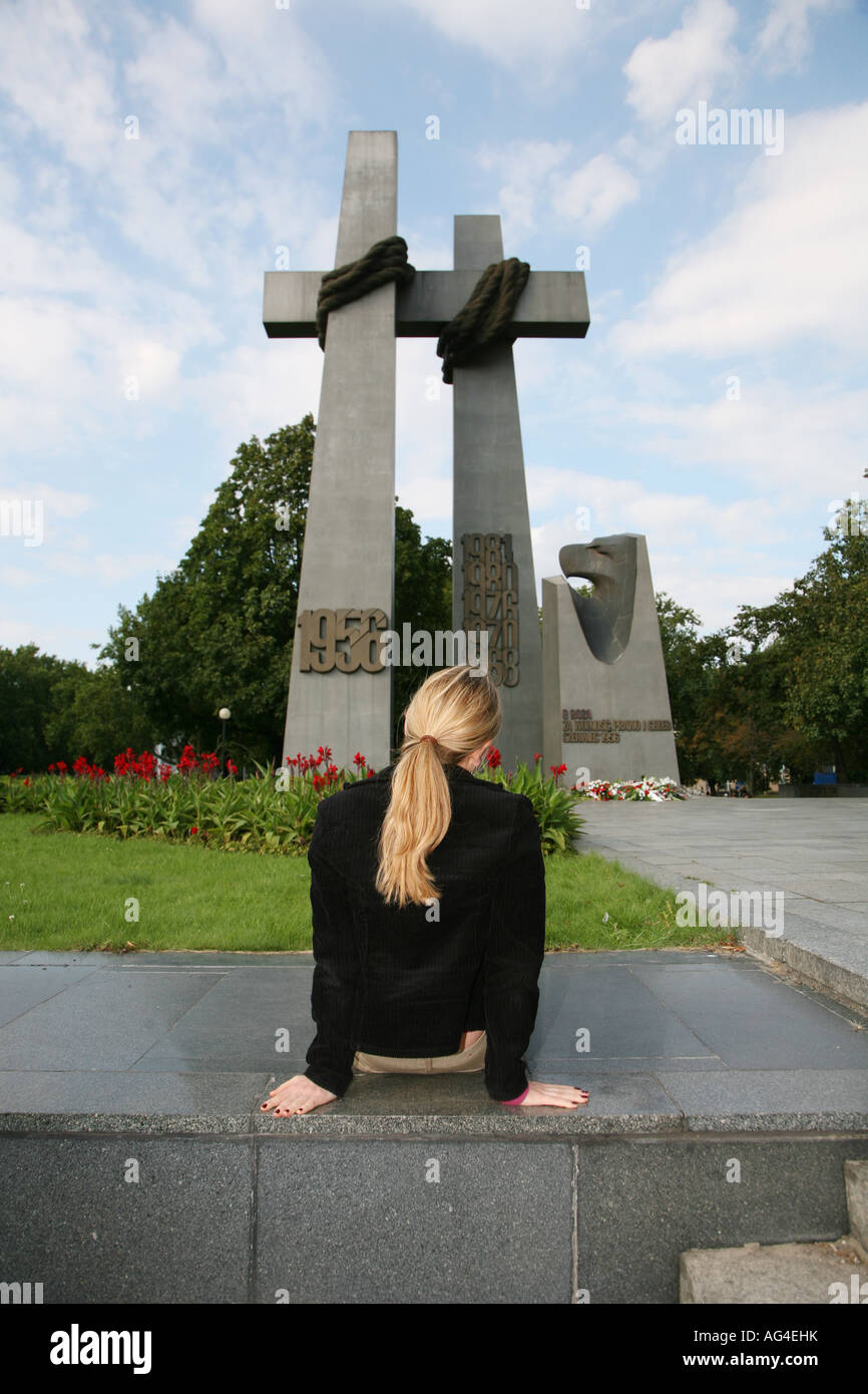 Donna seduta nella parte anteriore del memorial attraversa a Poznan in Polonia Foto Stock