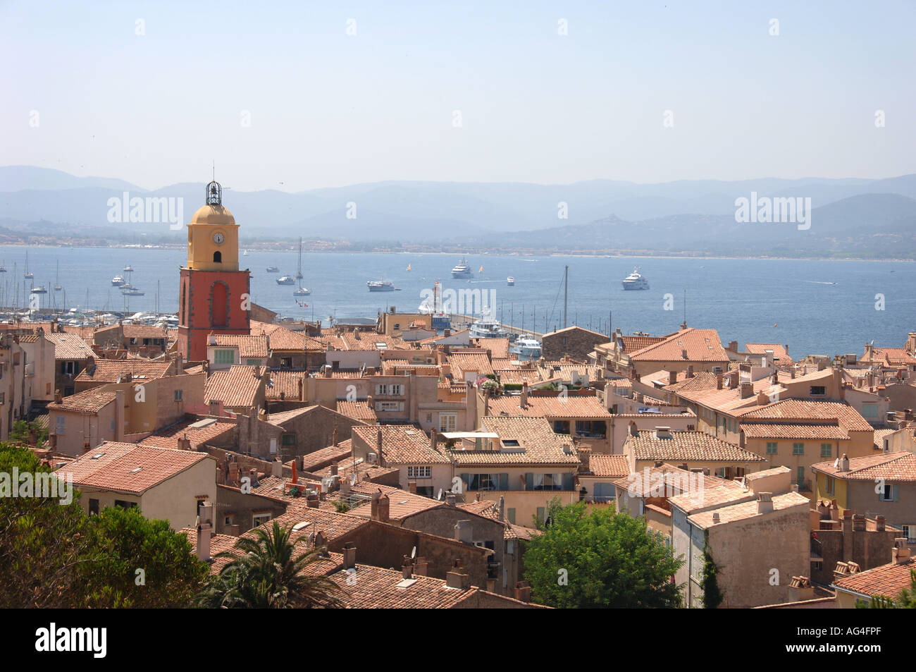 Vista della città di Saint Tropez da una posizione elevata vicino alla cittadella dietro la chiesa con il mare in background con yacht e barche. Foto Stock