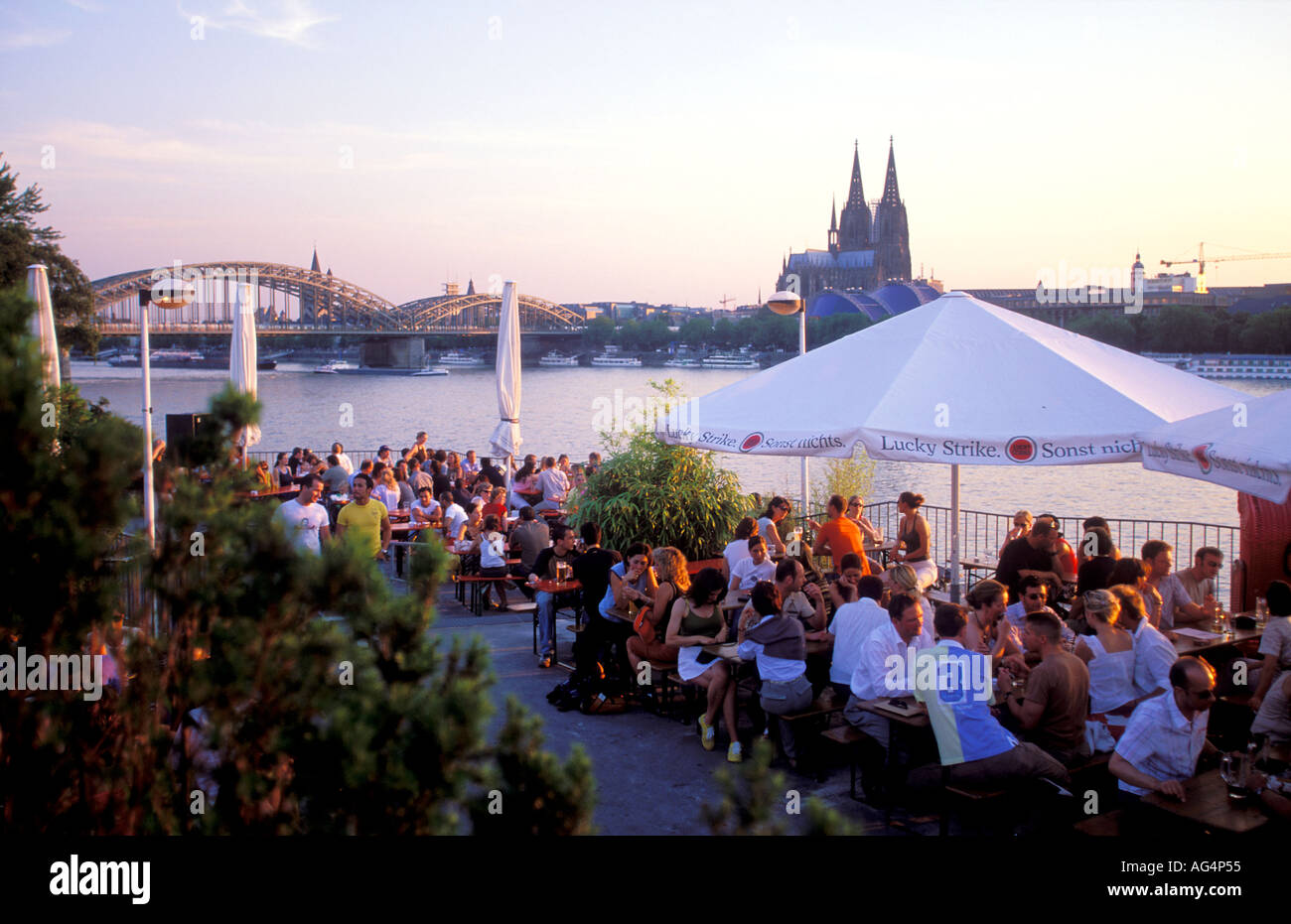La gente seduta al Rheinterrassen trendy bar e ristorante con vista sulla città vecchia e la Cattedrale di Colonia, Germania Foto Stock
