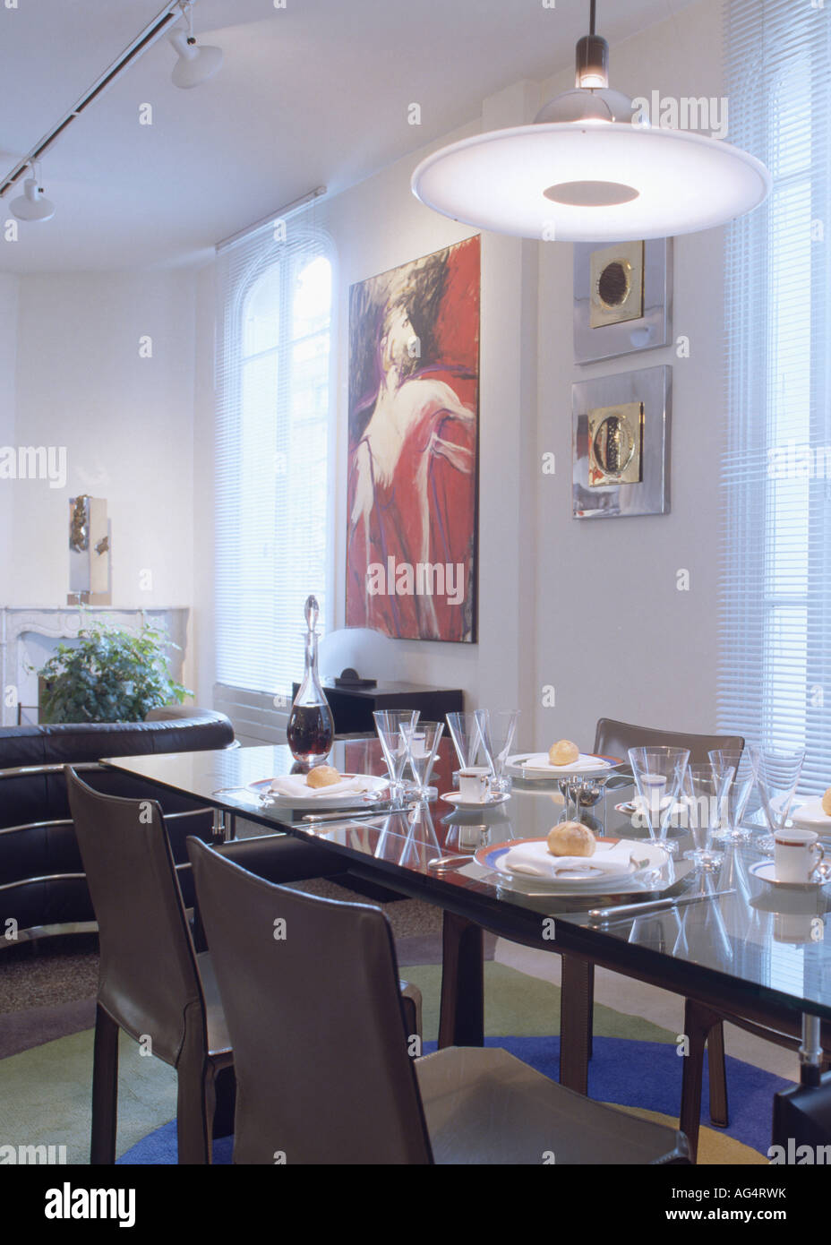 Disco circolare di luce sopra il raccordo tavola nera con le regolazioni del posto in bianca e moderna sala da pranzo in un appartamento a Parigi Foto Stock