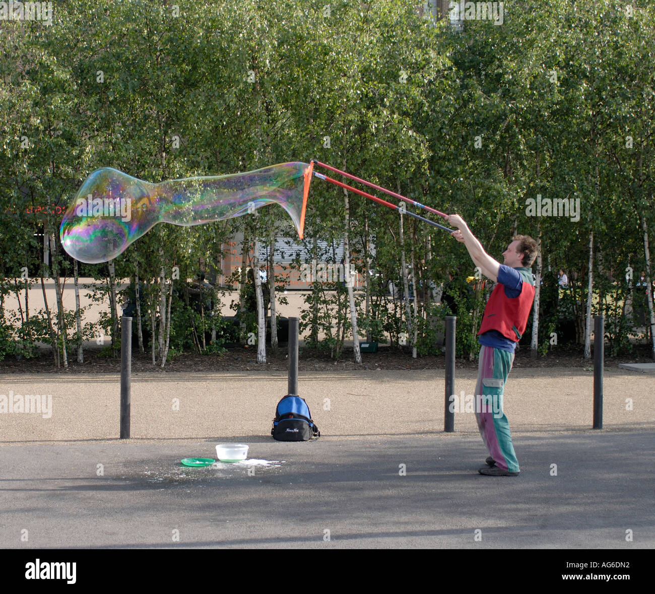 Un esecutore di strada gigante soffia bolle di sapone con colori Arcobaleno al di fuori della nuova Tate Gallery Southwark Londra Regno Unito 23 Giugno 2006 Foto Stock