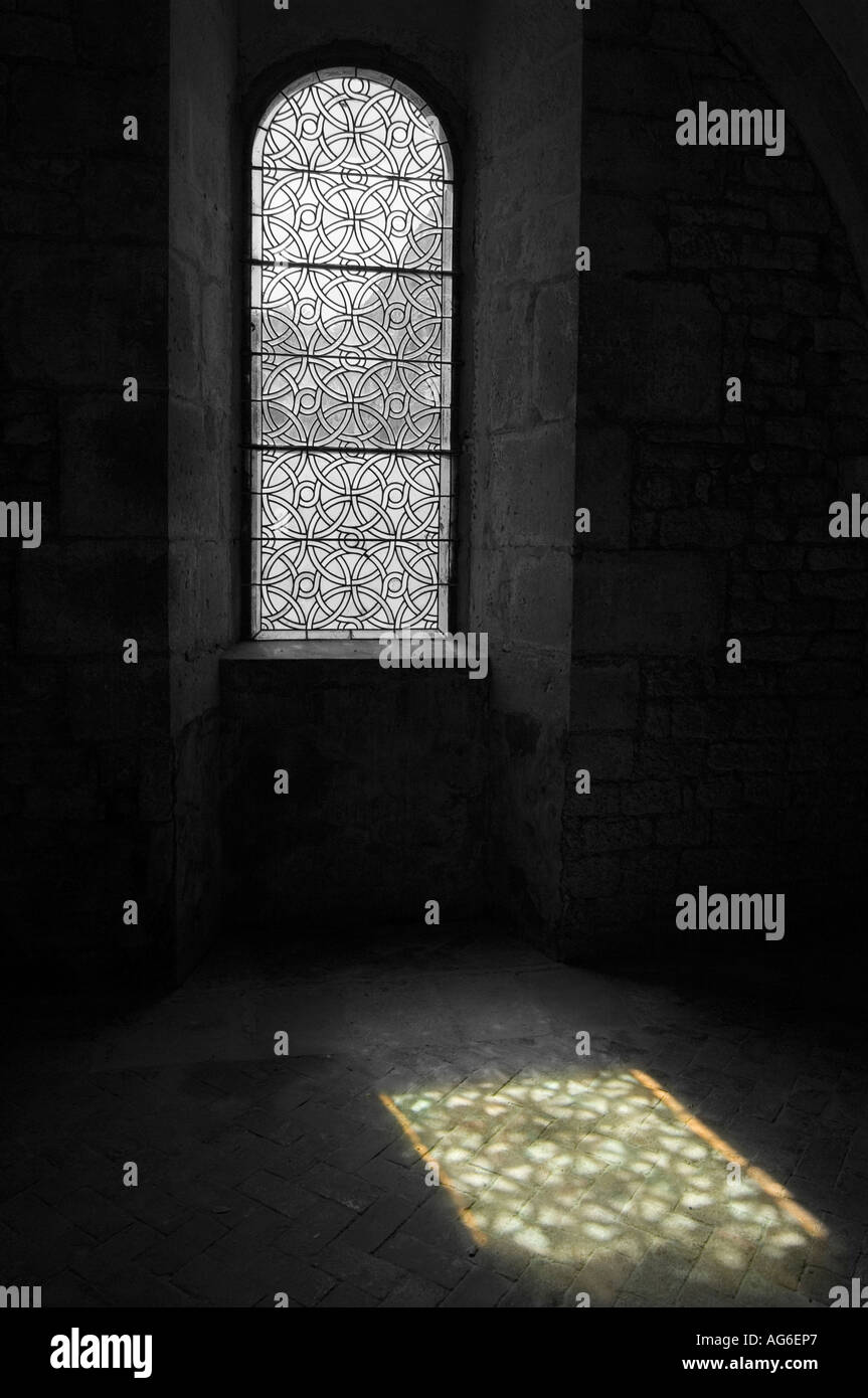 Medieval finestra ad arco con lo streaming di luce attraverso la fusione di una riflessione d'oro scuro sul pavimento in pietra interno Foto Stock