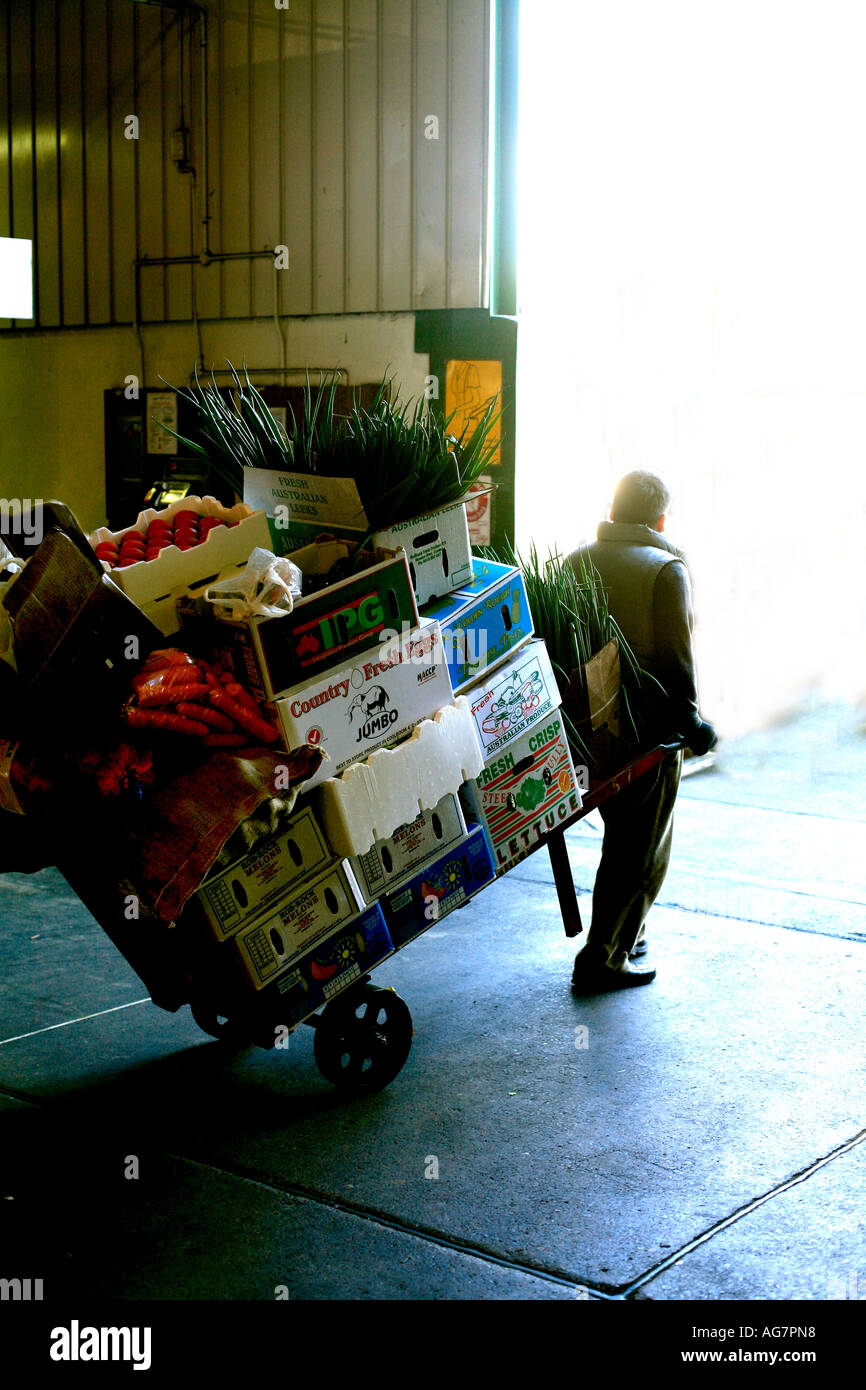 Un fornitore le ruote di un carro a mano di frutta delle verdure a Flemington Mercato in Sydney Australia Foto Stock