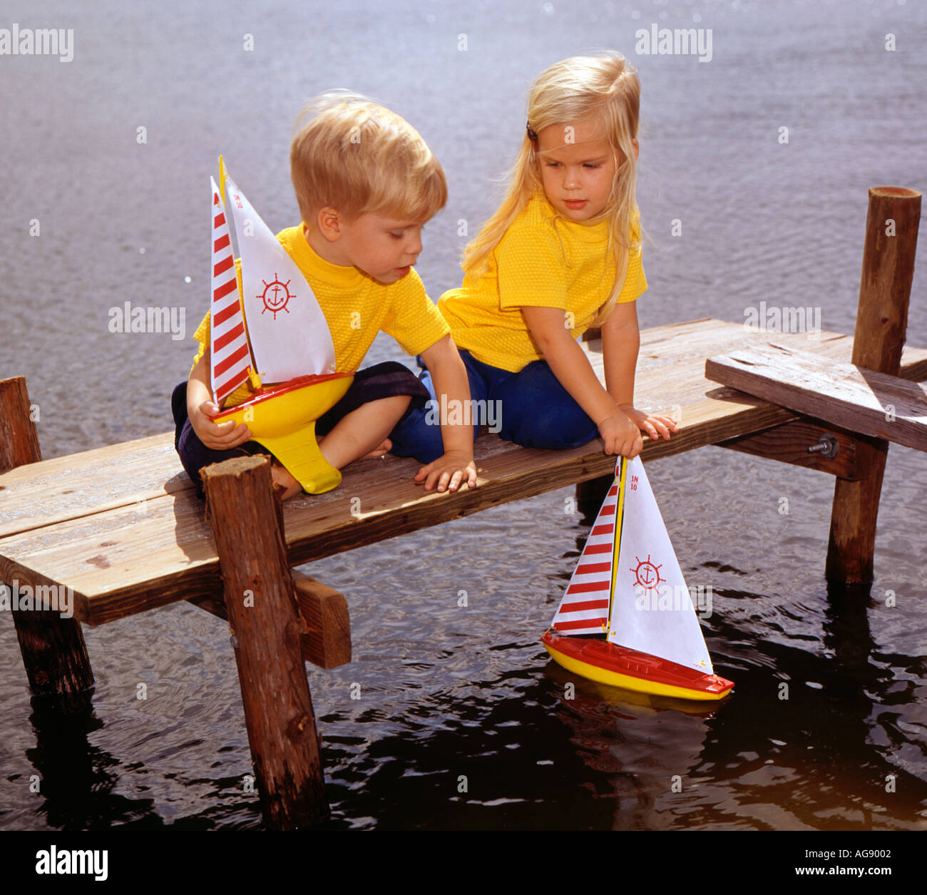 Piccolo Ragazzo e ragazza che gioca sul dock con il giocattolo in barca a vela Foto Stock