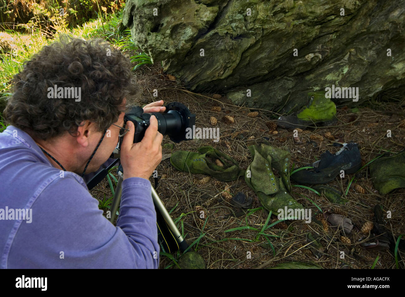 Fotografo prendendo un close up fotografia utilizzando fotocamera reflex digitale su un treppiede di un vecchio boot Foto Stock