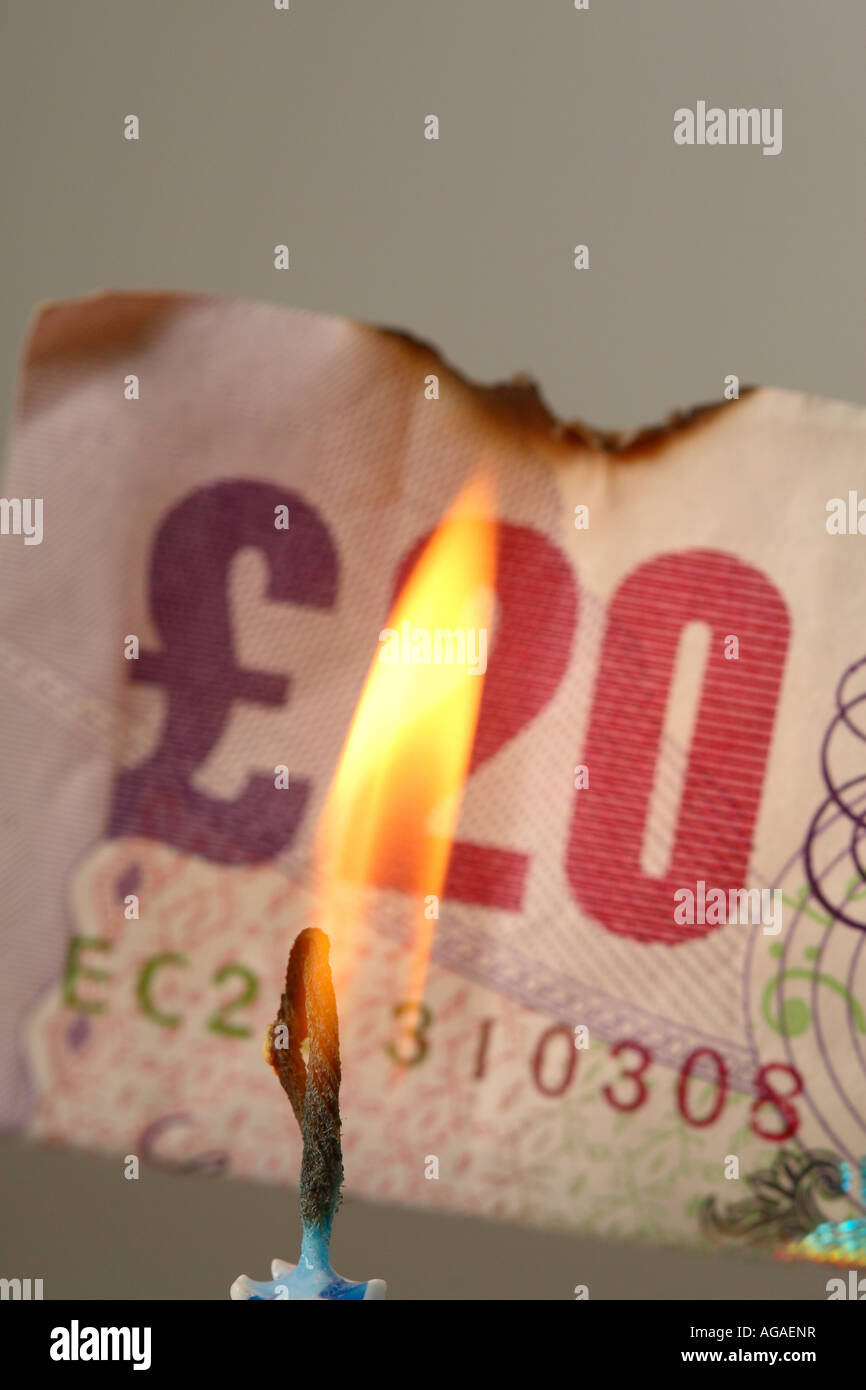 I soldi per masterizzare concetto £20 banconota con candela Foto Stock