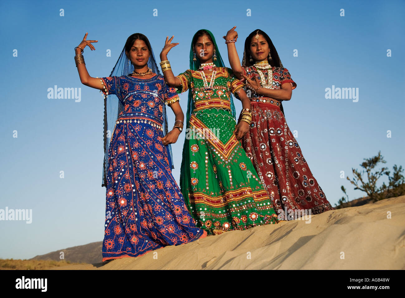 Giovani donne indiane in un splendidamente decorate sari eseguendo una tradizionale danza di Rajasthani deserto di Thar fuori Pushka India Foto Stock