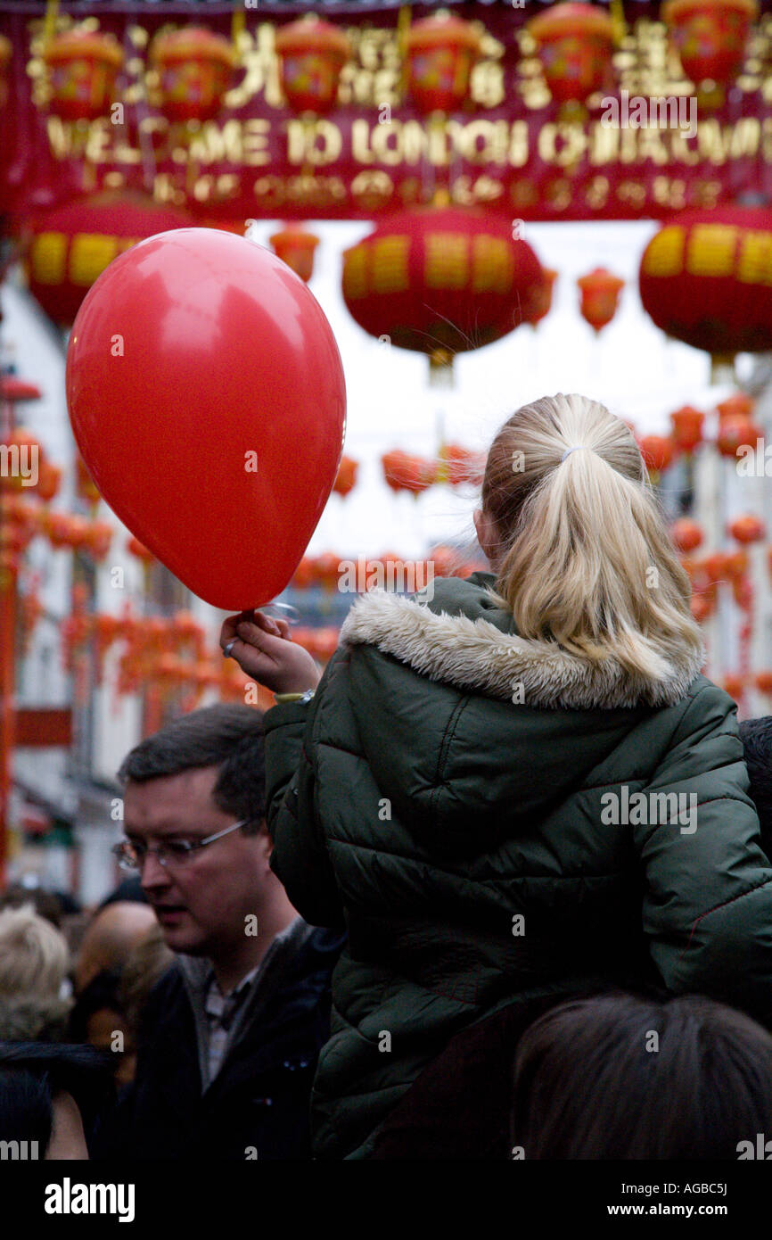 Ragazza giovane Padre s le spalle di contenimento palloncino rosso durante il Capodanno cinese Chinatown Londra 2007 Foto Stock