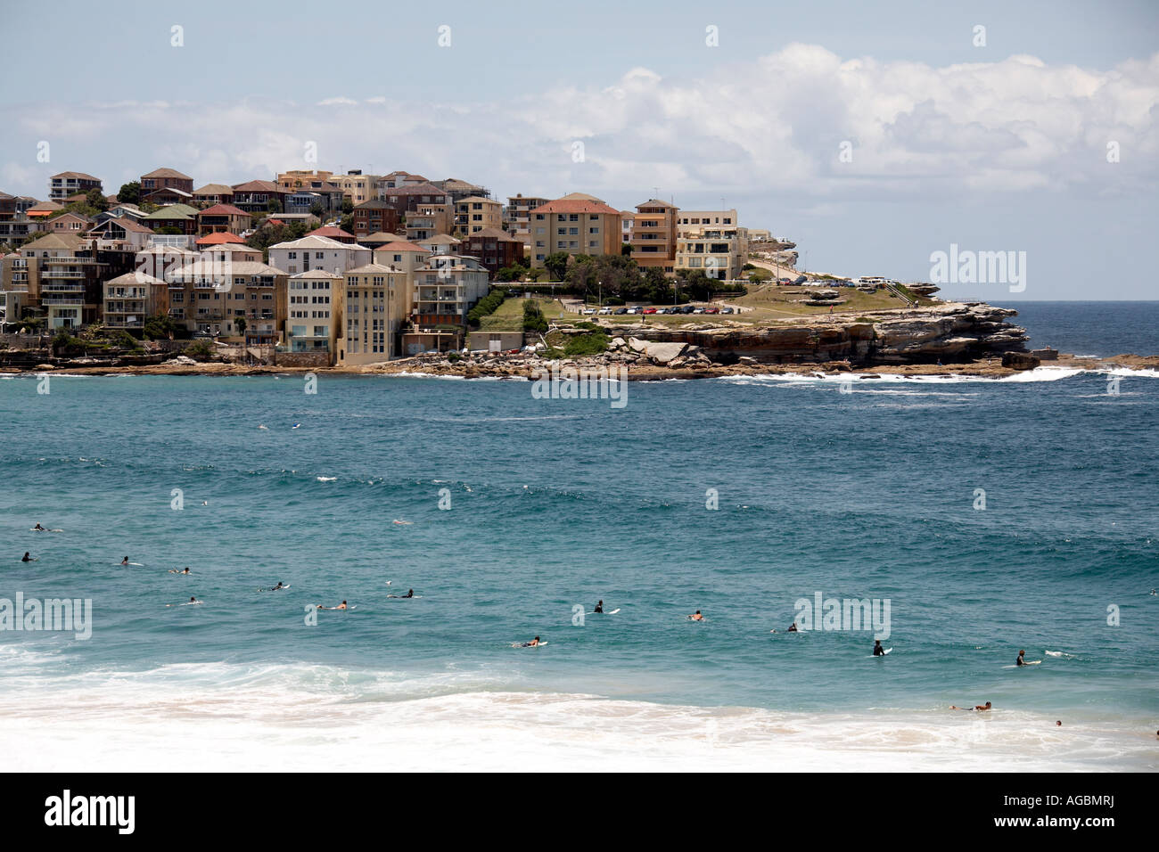 La gente di nuoto e in attesa di onde da surf con unità o edifici appartamento oltre a Bondi Beach Sydney New South Wales NSW Foto Stock