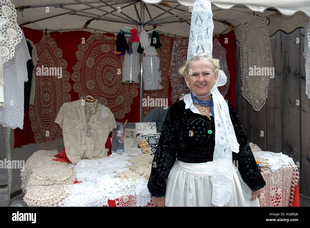 Accanto a lei Quimper stallo, una donna bretone vendita indossa in pizzo alto coiffe bianco una volta indossati dalle donne del "pays bigouden' Foto Stock