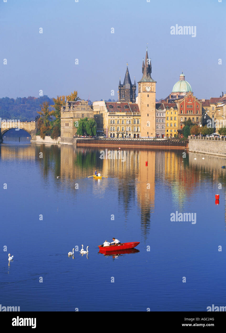 Canotto e cigni sul fiume Moldava sotto i cieli blu a Praga con la Città Vecchia Mills al di sopra Foto Stock