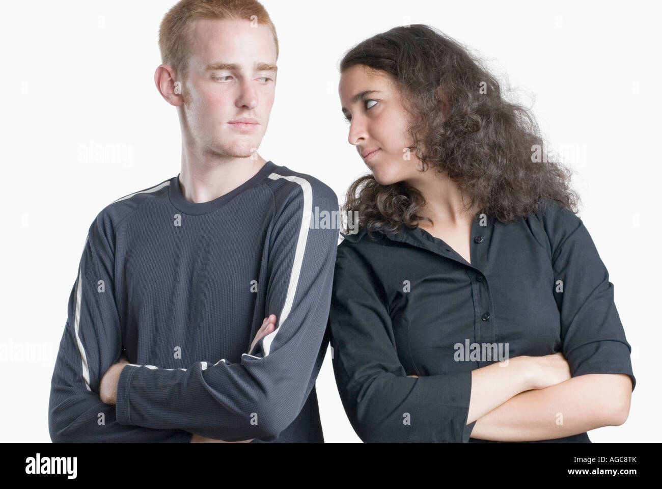 Close-up di una giovane coppia in piedi con le braccia incrociate e fissando tra loro Foto Stock