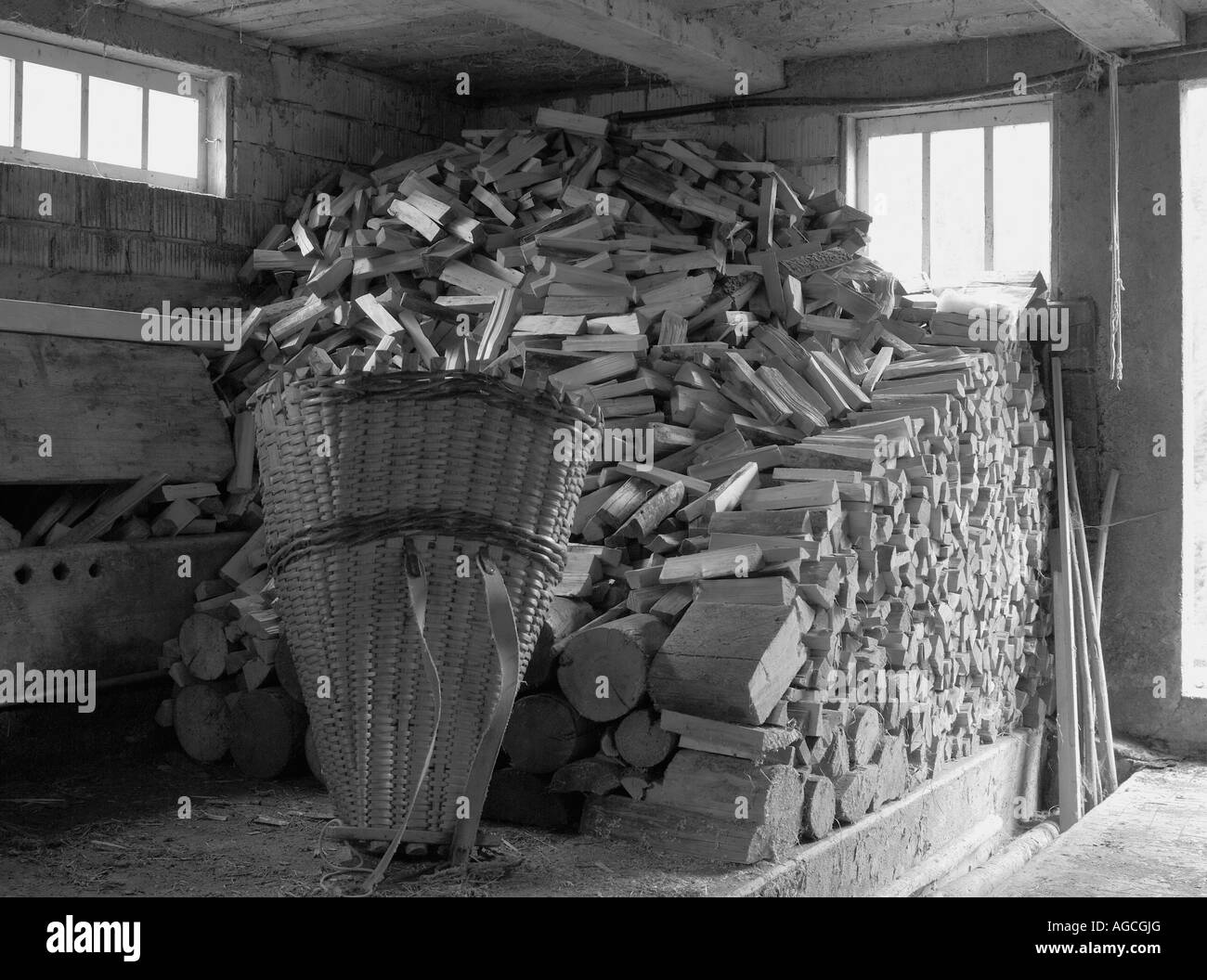 Vita rurale svizzera, edificio di stoccaggio contenente mucchi di tronchi di legno e un vecchio cesto tradizionale Foto Stock