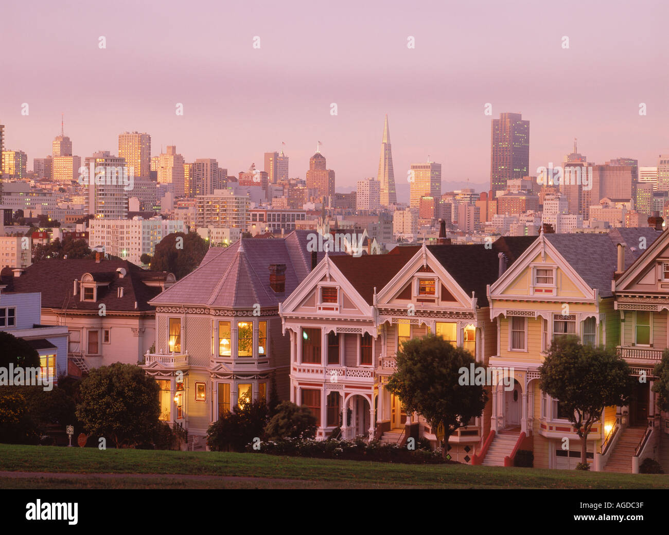 Case vittoriane lungo Steiner Street al crepuscolo con skyline di San Francisco Foto Stock