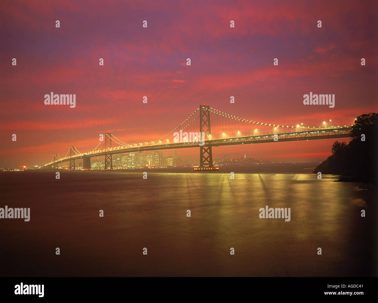 Oakland Bay Bridge sotto colorato tramonto cielo attraverso la baia di San Francisco Foto Stock