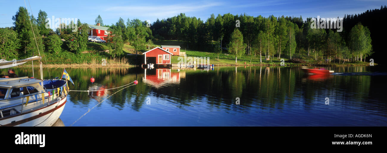 Barca a vela ormeggiata in tutta dal rosso country home e il boathouse lungo le vie navigabili interne sulla Costa Alta di Angermanland in Svezia Foto Stock