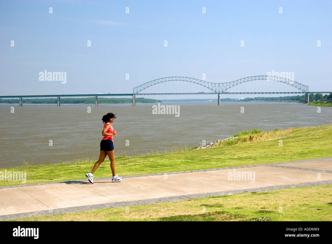 Donna fare jogging lungo il fiume Mississippi argine con la Hernando Desoto Memorial Bridge in background a Memphis, Tennessee Foto Stock