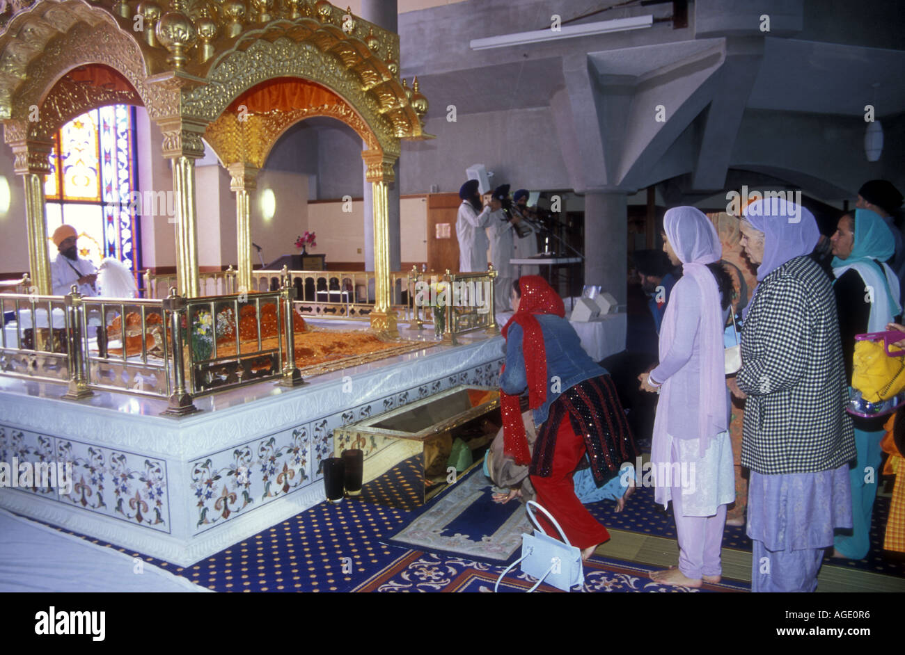 La religione sikh le donne pagano i loro aspetti al Guru Granth Sahib a Southall gurdwara. Londra esterna Foto Stock