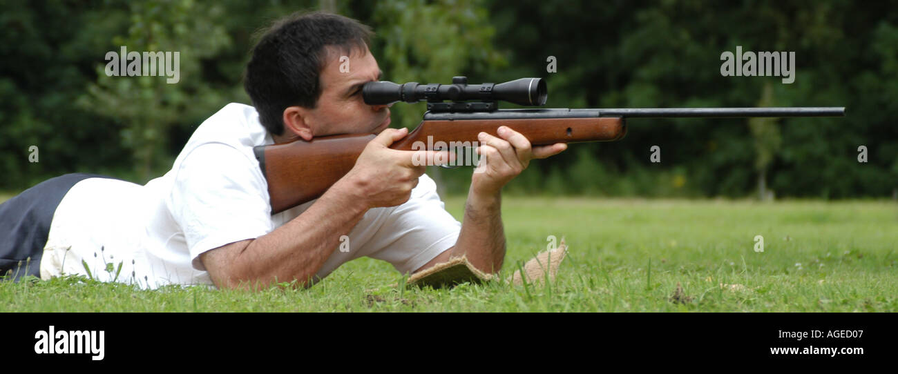 Uomo disteso verso il basso con un fucile prendendo obiettivo Foto Stock