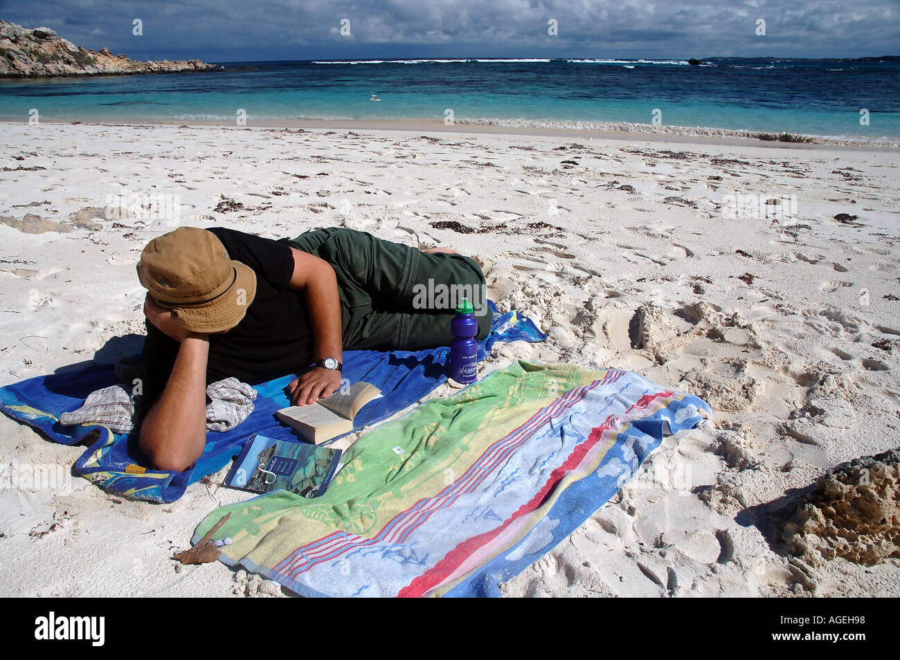 Uomo in vacanza la lettura di un libro sulla spiaggia della Baia di salmone Rottnest Island Western Australia MR Foto Stock