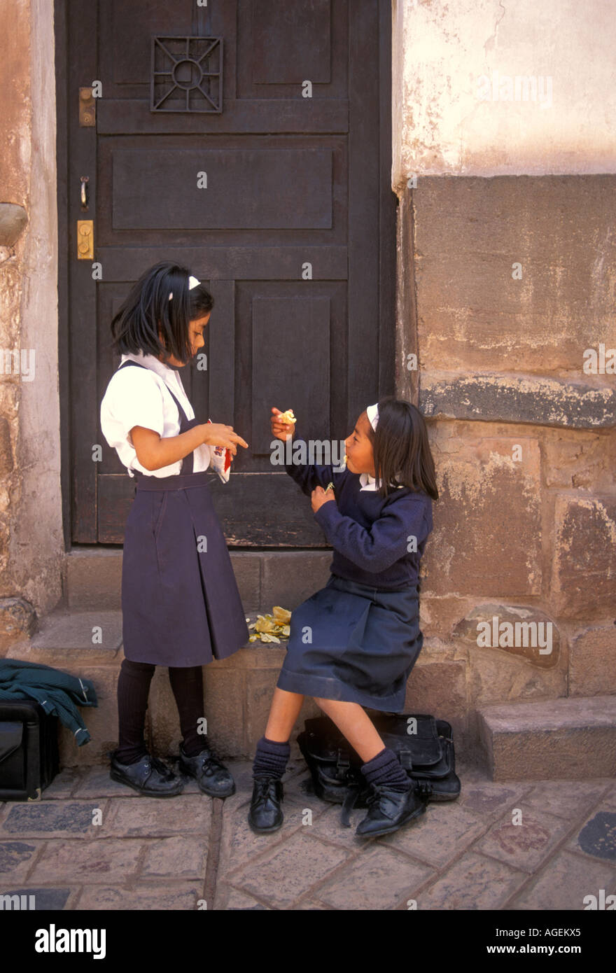 2, due peruviani, ragazze peruviano, scolare e scolari, indossano uniformi scolastiche, mangiando snack, Calle Ahuacpinta, Cuzco, Perù, Sud America Foto Stock