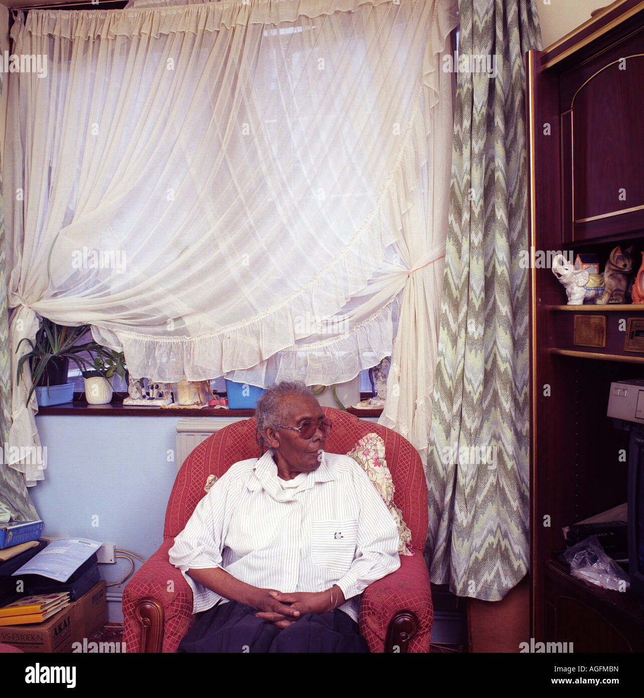 Un anziano afro-caribbean donna seduta nel suo salotto di casa. Foto Stock