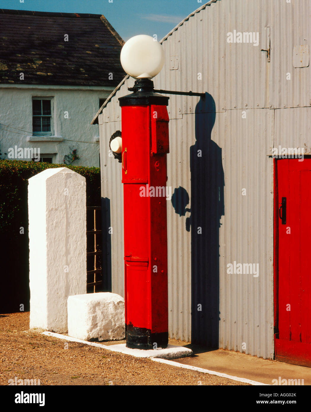 Stazione di benzina vintage vecchio stile in Irlanda rurale con un pompa di benzina rossa accanto al garage grigio Foto Stock