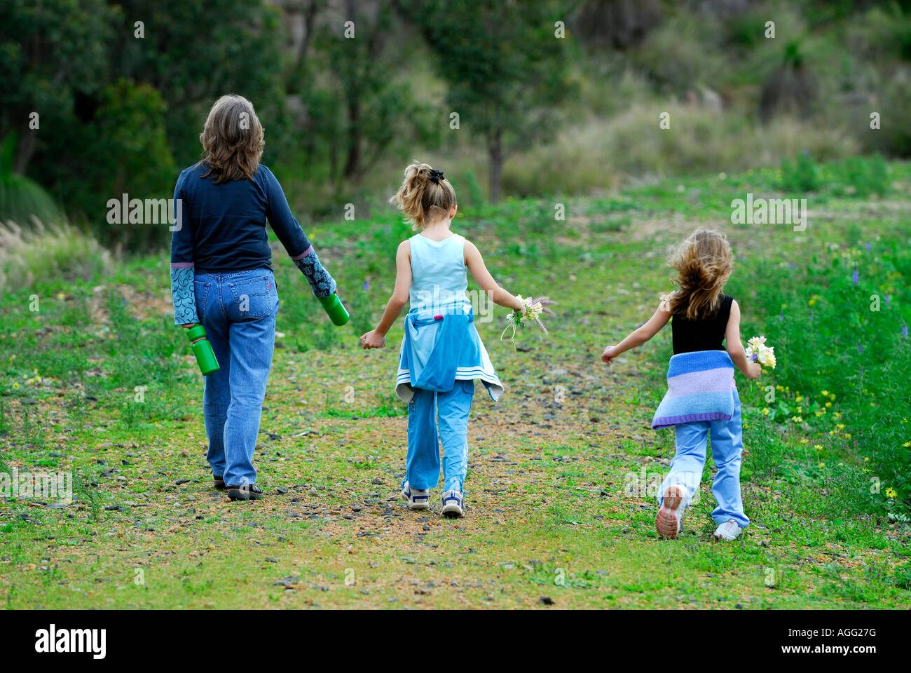 La madre e le sue due figlie a camminare sulla via di bush Foto Stock