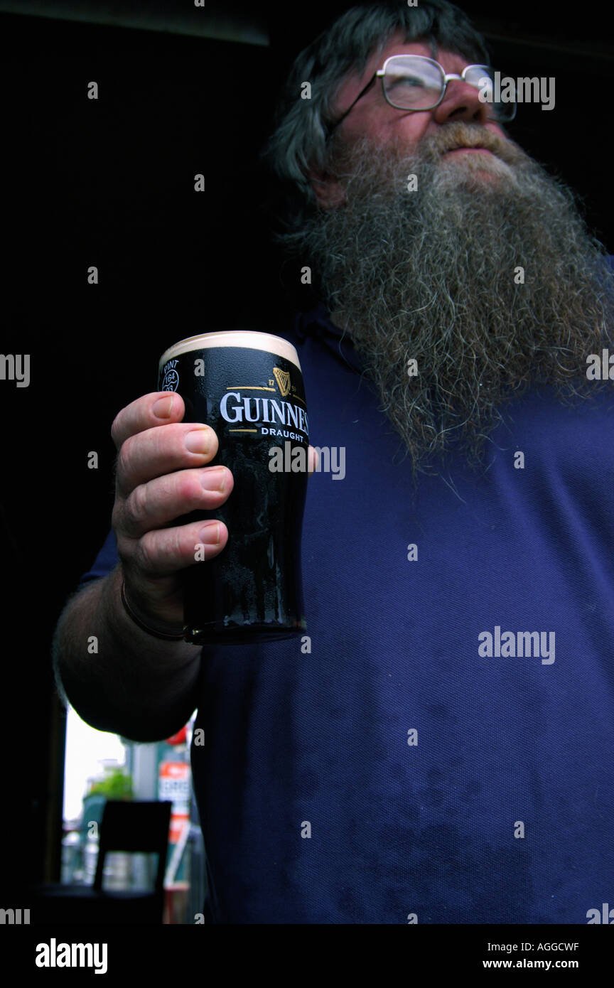 Sturdy barista con grande barba tenendo un bicchiere di birra, Irlanda Foto Stock