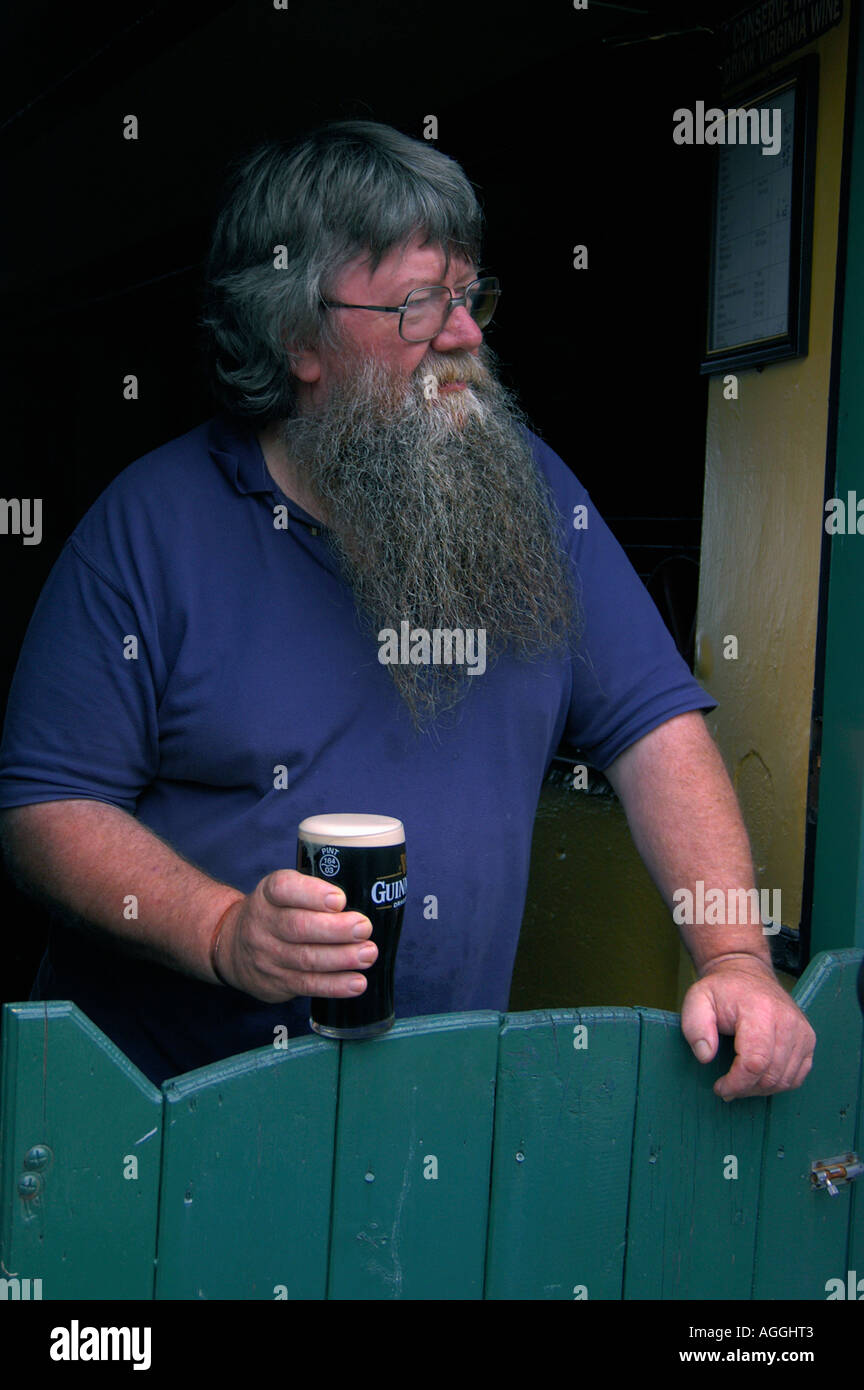 Sturdy barista con grande barba tenendo un bicchiere di birra, Irlanda Foto Stock