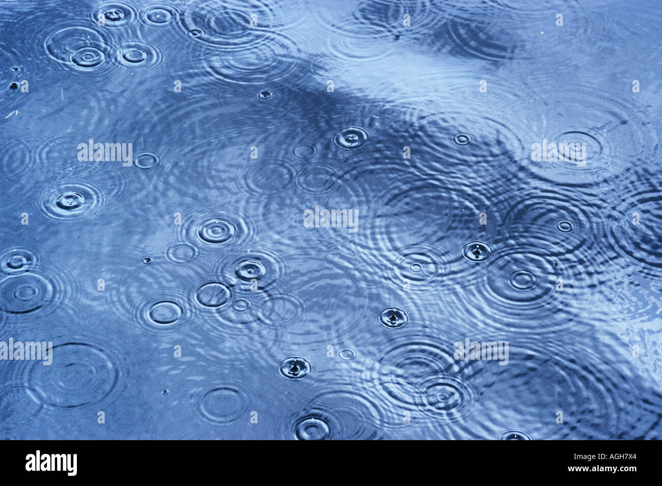 Le gocce di pioggia che colpisce la superficie di acqua e la creazione di increspature Foto Stock
