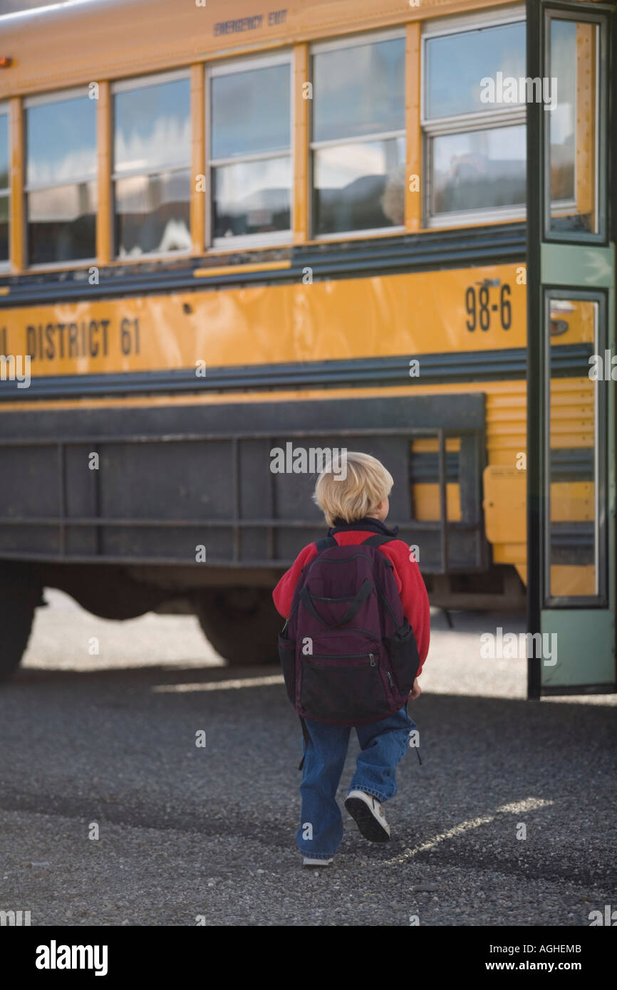 Poco capelli biondi ragazzo indossa il suo zaino sempre pronto a salire su un bus di scuola Foto Stock