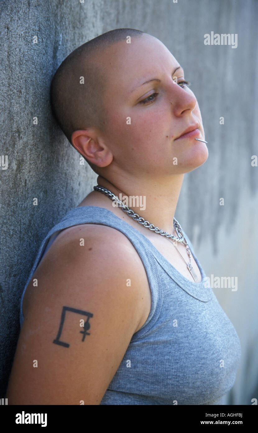 Moody ragazza con testa rasata piercing e tatuaggio Foto Stock