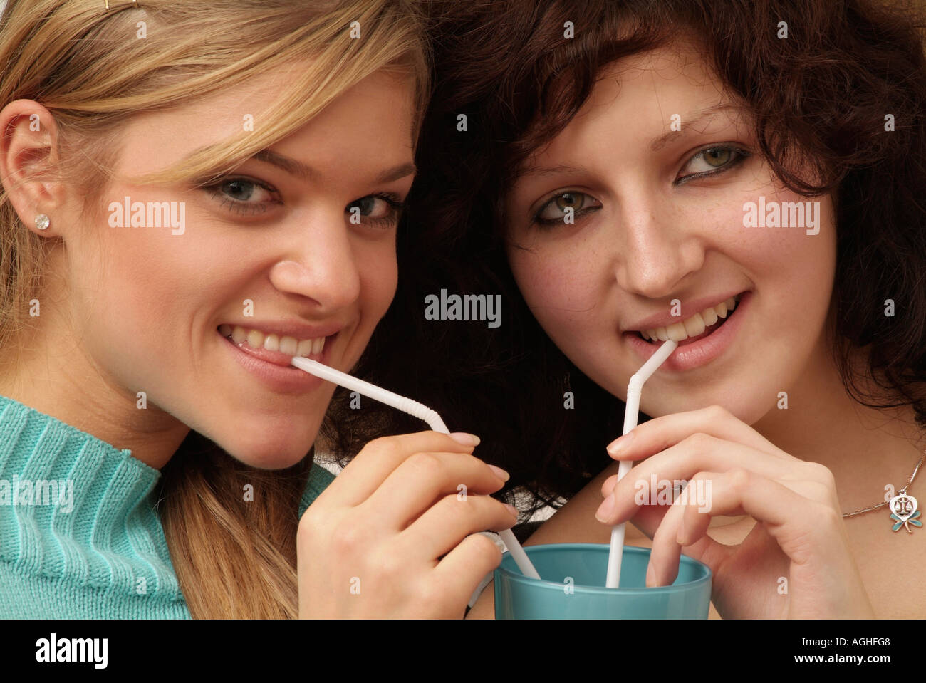 Due giovani donne che condividono bere utilizzando cannucce close up ritratto Foto Stock