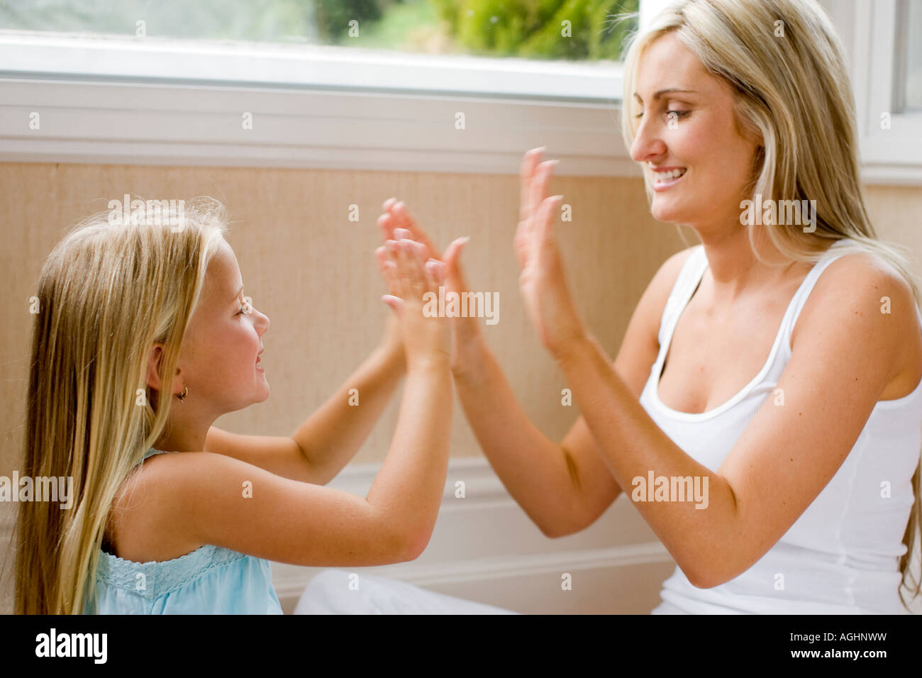 Madre e figlia giocando pat una torta Foto Stock