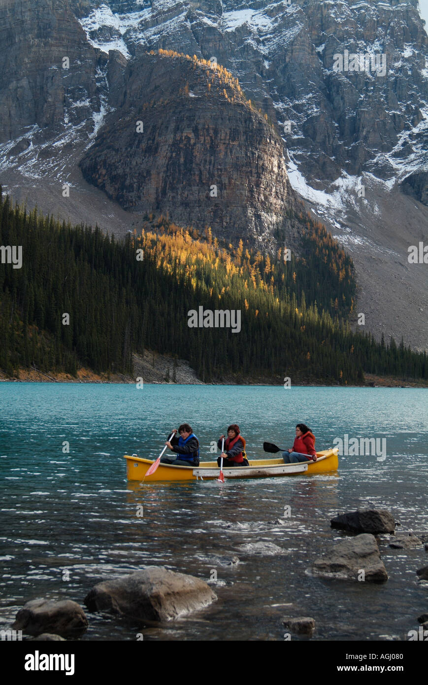 I turisti in un noleggio canoa e albero del sole sul larice alberi intorno al Lago Moraine Canadian Rockies Alberta Canada Foto Stock