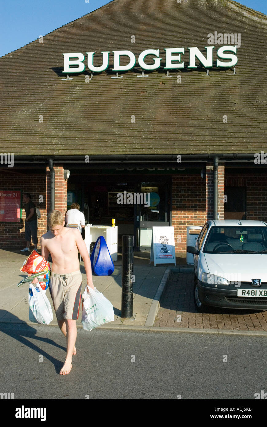 Ragazzo adolescente giovani emergenti dal supermercato Budgens Segala East Sussex Engladn Gran Bretagna REGNO UNITO Foto Stock