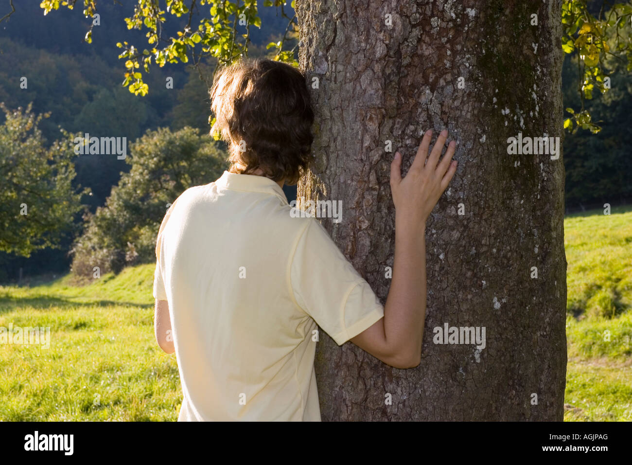 Donna che abbraccia pendente a tree Foto Stock