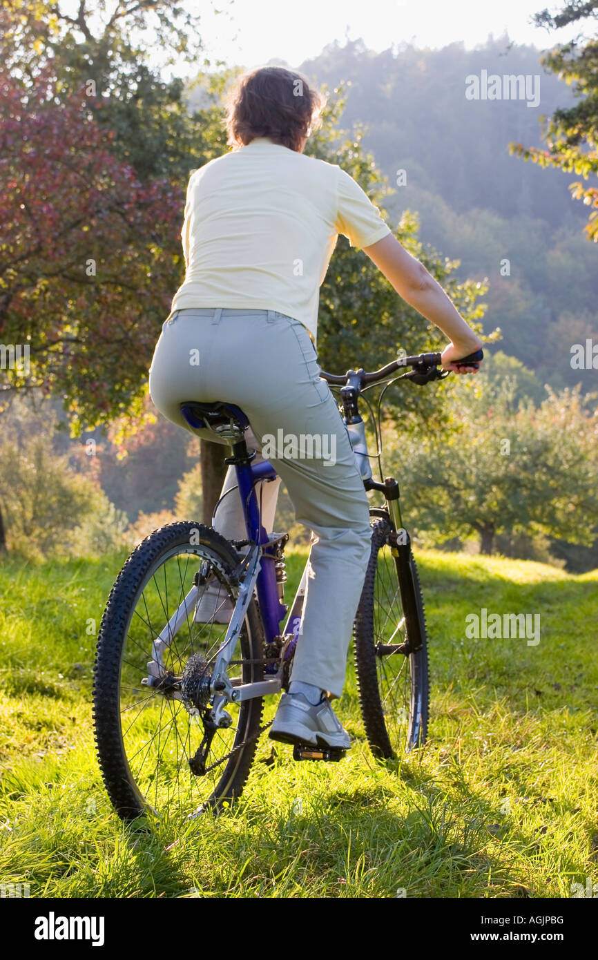 Donna su una mountainbike al tramonto in autunno Foto Stock