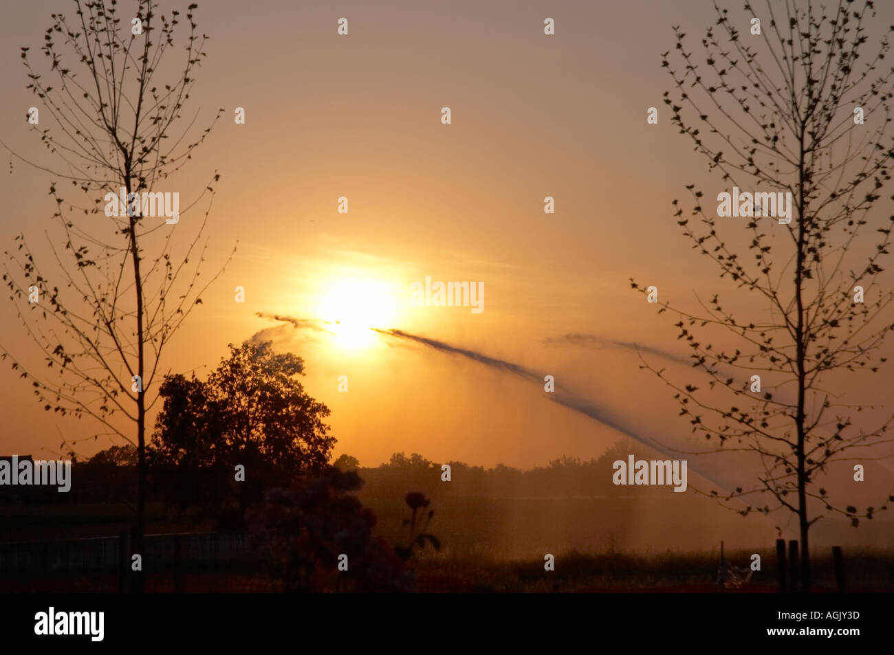 Retroilluminazione del rosso tramonto estivo e le pompe di irrigazione in campagna Gossolengo Piacenza Italia Foto Stock