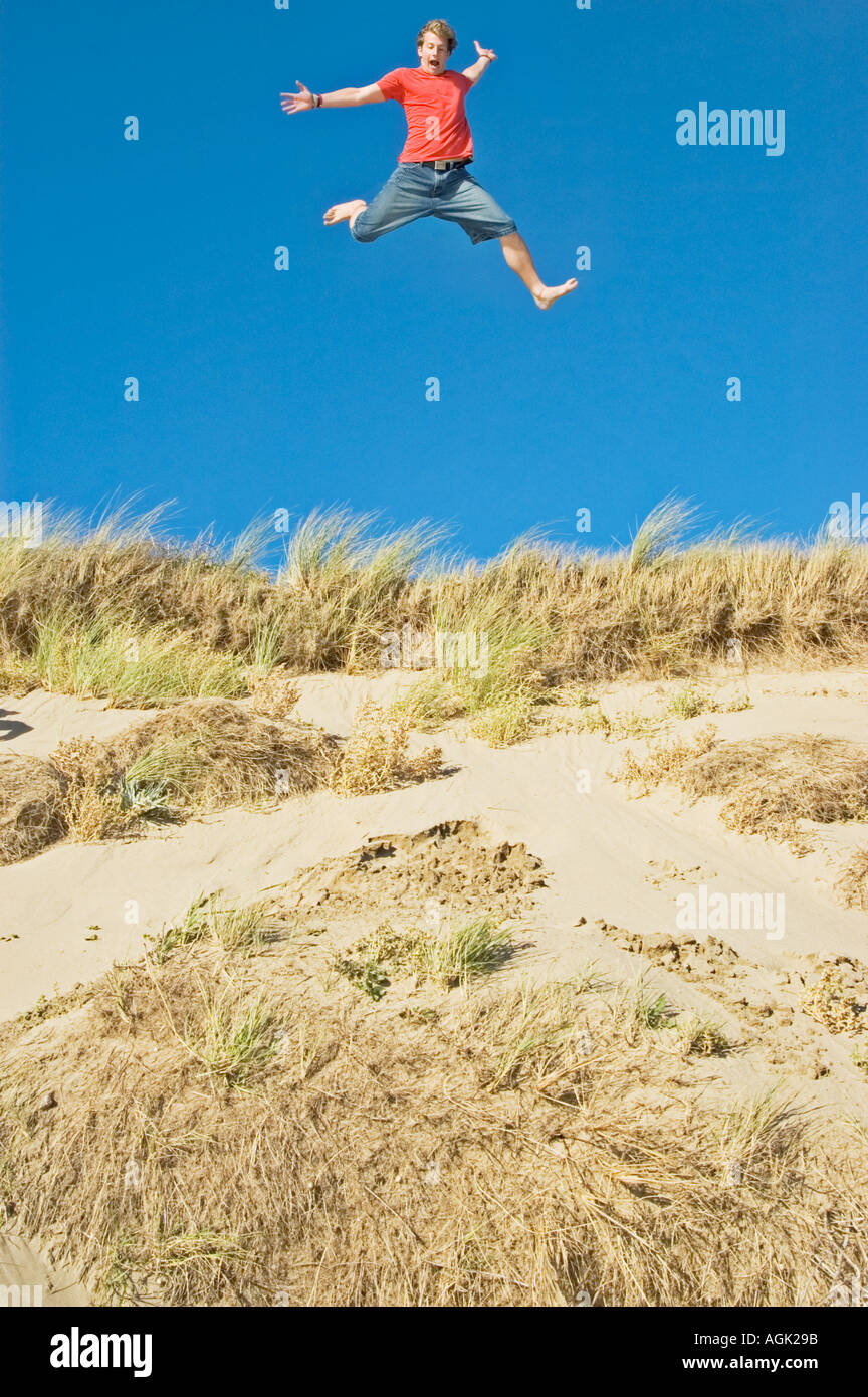 Giovane uomo saltando da una duna di sabbia Braunton Burrows Devon UK Foto Stock