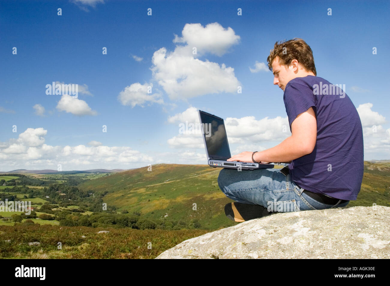 Giovane uomo utilizzando il computer portatile in aperta campagna REGNO UNITO Foto Stock