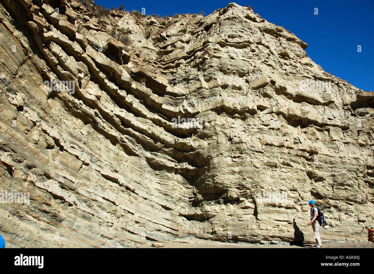 Una femmina di un geologo in piedi di fronte ad un affioramento di strati di arenaria e di scisto, Spagna meridionale. Foto Stock