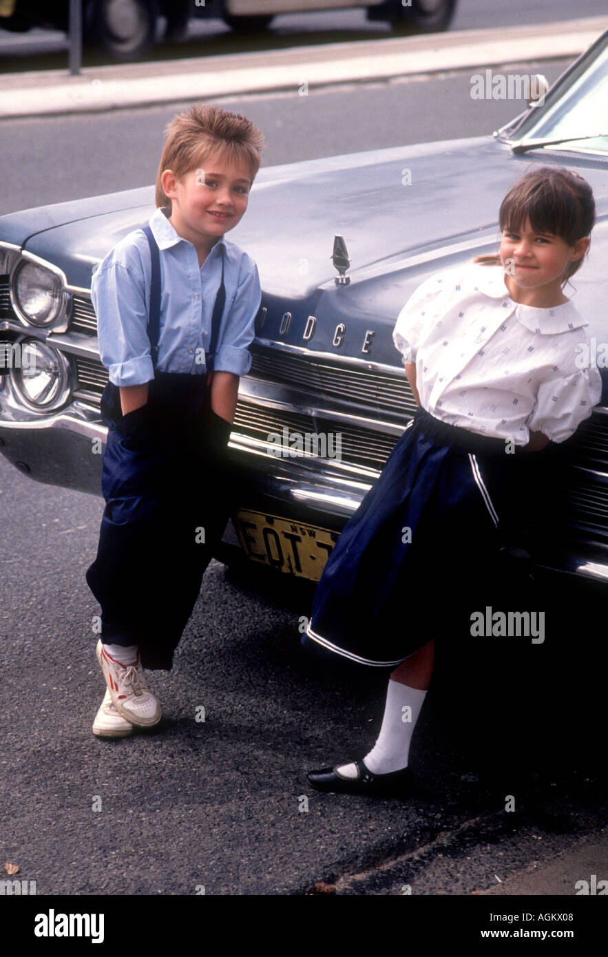 I bambini vestiti di modellazione in una strada di città con americano degli anni cinquanta, Dodge auto Foto Stock